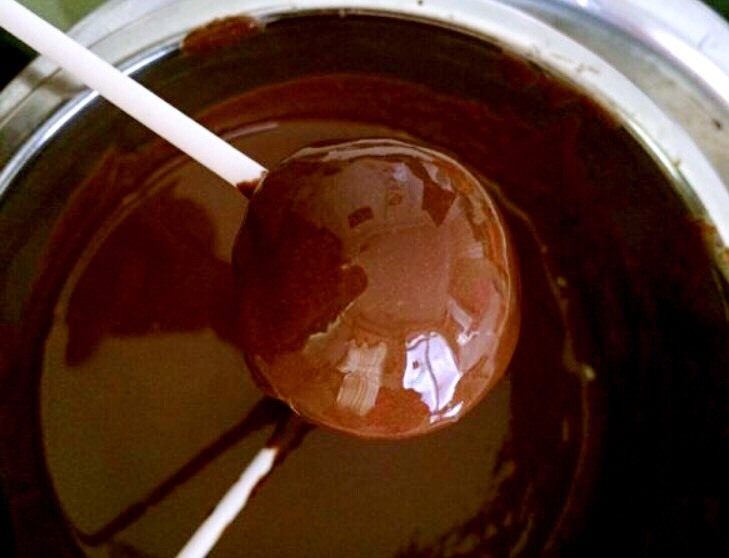 巧克力棒棒糖蛋糕,棒棒糖小棒放巧克力中沾一下，插入小蛋糕中心，然后放入融化的巧克力中旋转一下，提起，再漫漫旋转稍凉