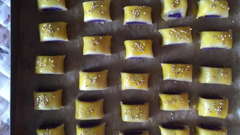 紫薯一口酥,烤盘提前铺好油纸，把切好小剂子放在烤盘里，涂上一层蛋液，撒上少许芝麻