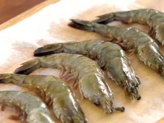 豉油皇大虾,接着从虾头与身体连接处沿背部剪开虾壳约两厘米，挑出虾肠，洗净并用纸吸干水份