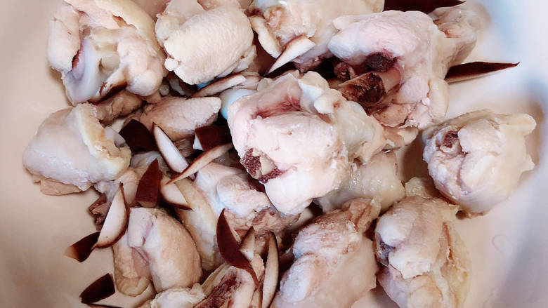 姜葱冬菇蒸滑鸡,锅中烧开水，加入料酒，下入鸡翅根，煮去血水祛除腥味，捞出洗净，放入大碗中。