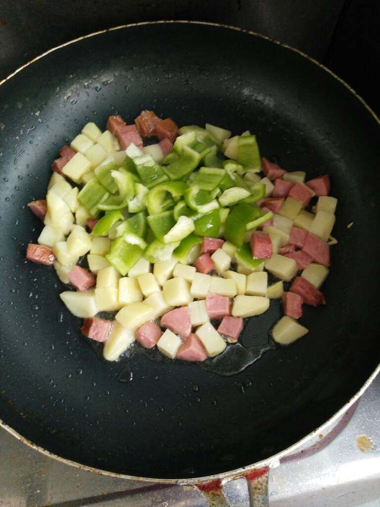 火腿土豆炒包椒,蒜片炝锅，加入土豆丁、火腿丁翻炒，再加入包椒、盐翻炒