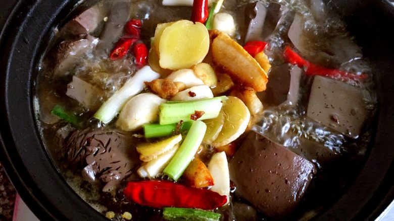 牛血旺#健康美颜餐#,将炒香的葱姜蒜放入砂锅中，大火煮开后转小火炖十分钟。