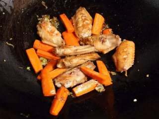 黄焖鸡米饭,接着放葱、姜末和胡萝卜炒几下，放入鸡翅。