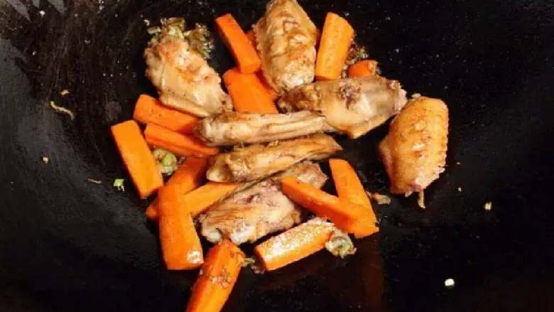 黄焖鸡米饭,接着放葱、姜末和胡萝卜炒几下，放入鸡翅。