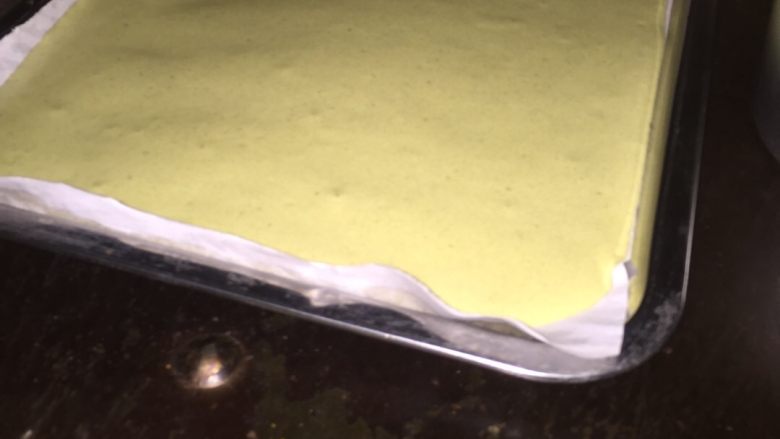 抹茶芒果卷,在烤盘中垫张纸把融合好的蛋糕浆倒入盘中，送进烤炉，160度18分钟（先把烤箱预热160度）