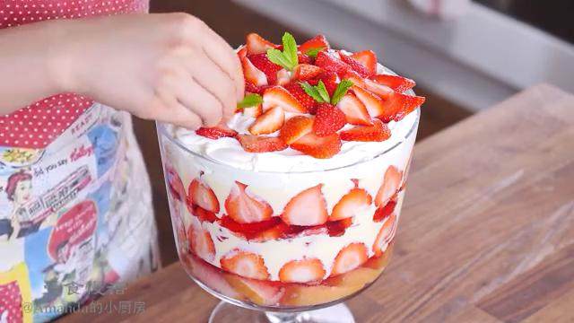 草莓布丁杯,在奶油上面围一圈草莓片，剩下的草莓块堆在中间，用薄荷叶点缀完成。