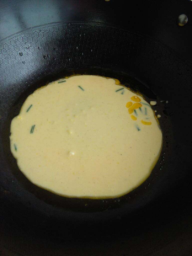 黄金饼,第六步，缓缓倒入面粉鸡蛋液，遇热开始慢慢的成型了，然后还要翻转一次，两面都煎到;现在饼的边缘己经开始脆了。