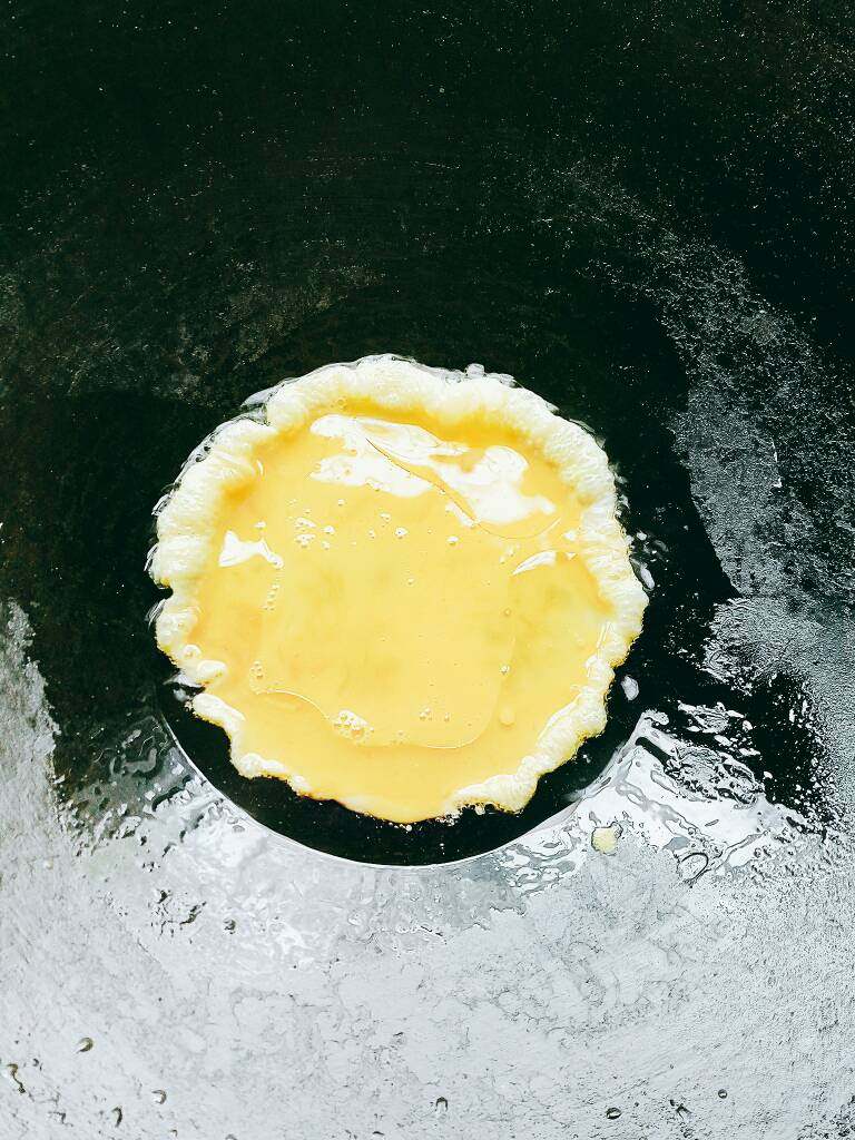 韭菜炒鸡蛋,锅中放油把鸡蛋放入摊开煎好