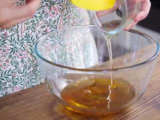 蛋黄莲蓉月饼,把食用碱放入大碗中，倒入半小勺清水溶解，倒入蜂蜜、花生油，用蛋抽搅拌均匀