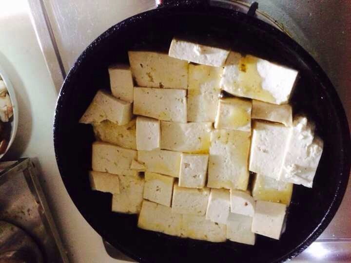 双菇豆腐煲,平底锅里放少许油，将豆腐块放入，小火慢煎，煎好一面翻过煎另一面。