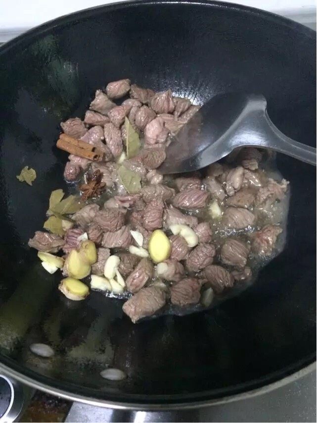 土豆烧牛肉,翻炒至牛肉完全变色后加入姜、蒜、八角、桂皮、香叶继续翻炒