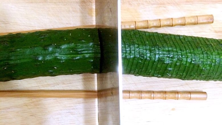 蓑衣黄瓜,刀子下落与黄瓜的角度呈90度，切片，底部不切断，放筷子就是防止切断，切完整根黄瓜