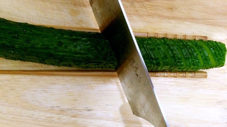 蓑衣黄瓜,黄瓜翻转180度，没切的部分朝上，此次切片，刀子与黄瓜的角度变为45度斜切，依次切完