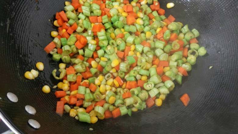 腊肠煲饭,热油下锅，放适量的盐一起将胡萝卜，玉米和豆角放下去炒至入味。