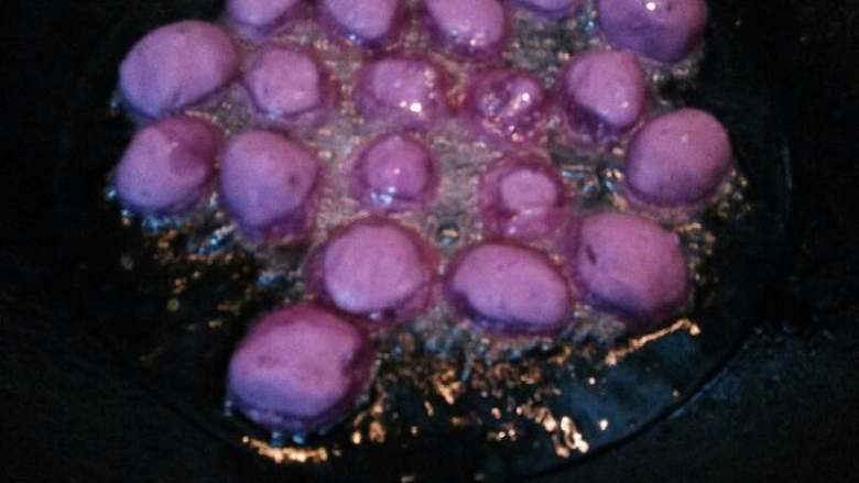 紫薯蜂蜜丸子#甜蜜美味#,待油温上来，把紫薯丸子一个个放入油锅，小火炸
