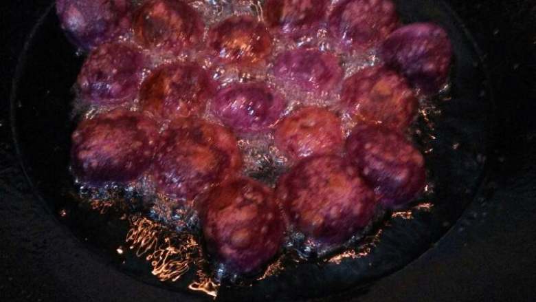 紫薯蜂蜜丸子#甜蜜美味#,一面炸变色后翻面，直至紫薯丸子膨胀得圆又大就说明好了