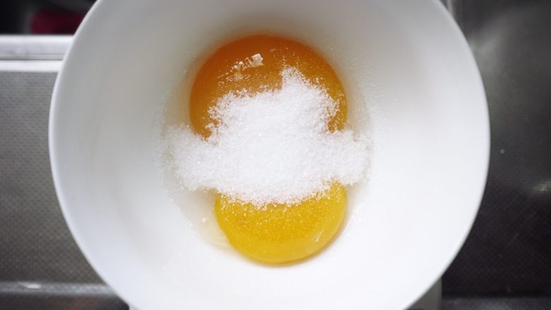 淡淡草莓香的杏仁小蛋糕,将剩余的白砂糖倒入蛋黄中，用手动打蛋器搅拌均匀直至白砂糖完全溶解。