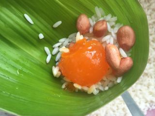 咸鸭蛋粽,头尾各放糯米，中间放入半个咸鸭蛋黄和几个花生