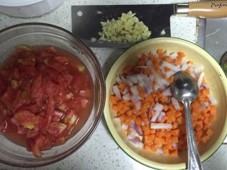 番茄肉酱意面,在煮面的过程，把胡萝卜，洋葱和刚煮爆开的番茄去皮，切丁备用