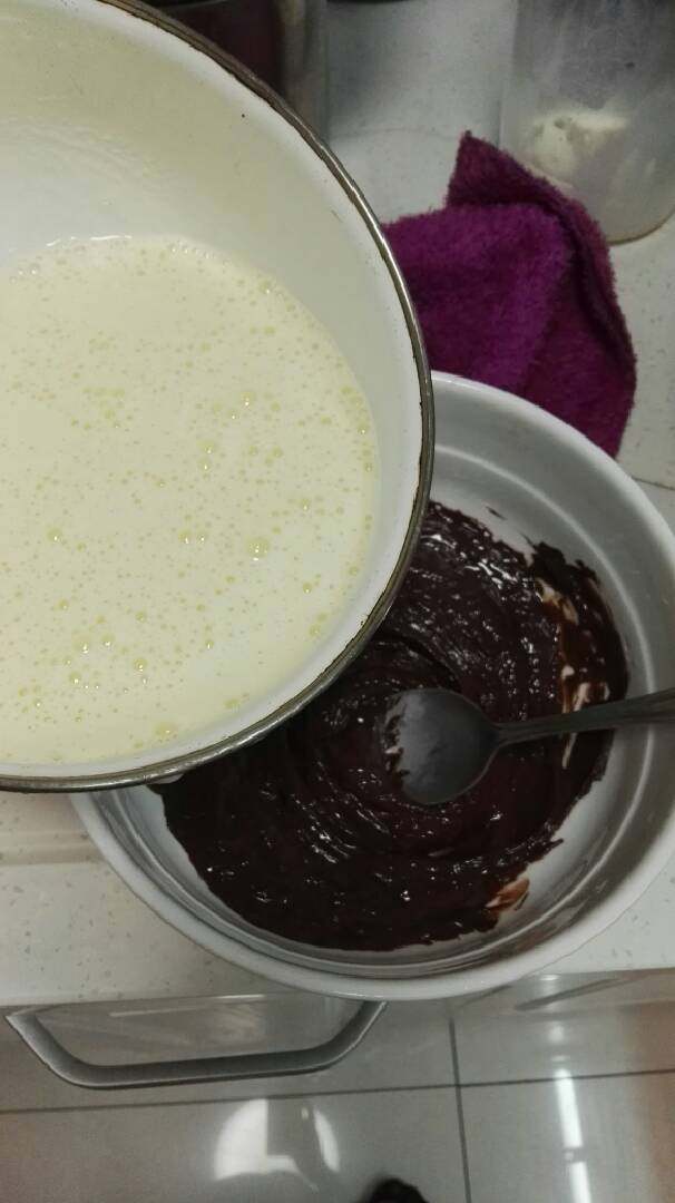 巧克力慕斯蛋糕,再将有蛋黄的牛奶慢慢倒入巧克力中，同样一开始要边倒入边顺时针打发，这里需要慢慢搅拌，不然巧克力容易结块，最后等巧克力全融化于牛奶液中时，再将牛奶全部倒入，充分打发