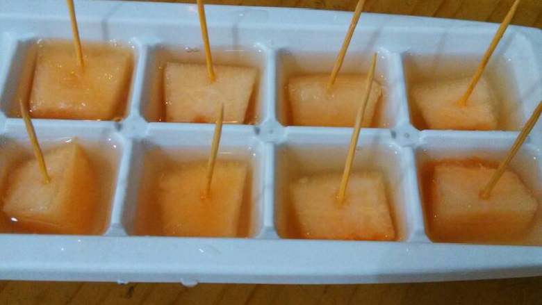蜜瓜遇上冰,这是另一种做法，哈蜜瓜切大丁，放入冰格，在哈蜜瓜中间插上牙签，每格都倒入蜂蜜水，同样放进冰箱冷冻一夜