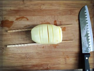 芝士培根焗土豆,土豆下面搭筷子夹开始切片。放筷子是为了不要切断噢。