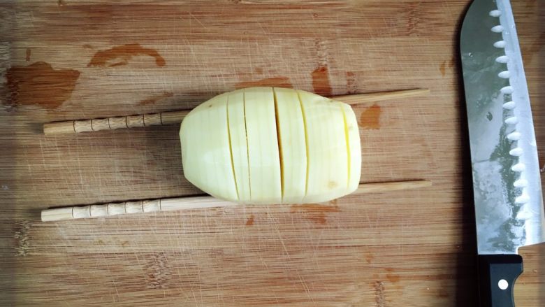 芝士培根焗土豆,<a style='color:red;display:inline-block;' href='/shicai/ 23'>土豆</a>下面搭筷子夹开始切片。放筷子是为了不要切断噢。