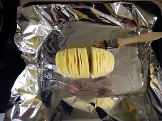 芝士培根焗土豆,捞出后沥干用少许盐腌制十五分钟。表面涂满橄榄油或黄油。用锡纸包裹。