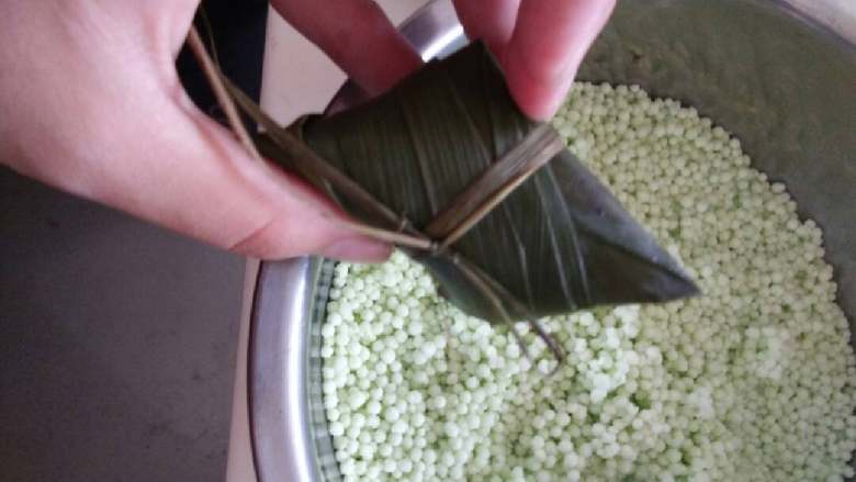 柠香水晶粽,将粽叶折过来盖住西米，整理好形状后用马莲草扎好