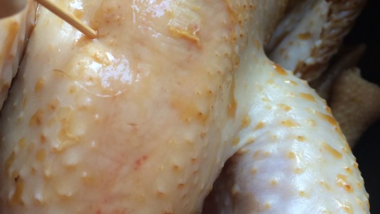 酱油鸡,用牙签在腿上，脑前扎小孔，拿葱占生抽在鸡身上擦一下，淹制半小时，几分钟翻转一下
