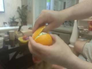 手剥甜橙,左手转动橙子，右手拇指渐渐剥入半边橙皮内
