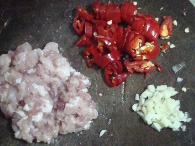 毛豆炒肉末,5. 锅内加油烧热下入红辣椒段、蒜末爆香。