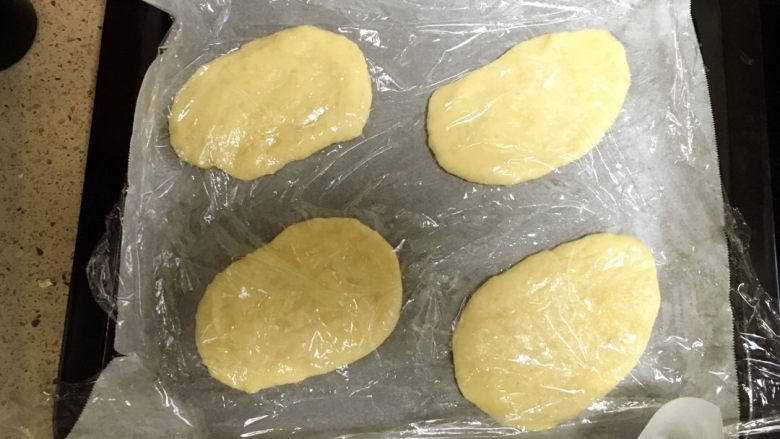 香葱芝麻培根面包,用擀面棍擀成椭圆形后加盖保鲜膜二次发酵。方法用前。这次也需要半小时左右。