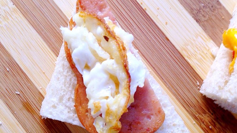 简易三明治,午餐肉切三角形，鸡蛋切碎叠在吐司上。