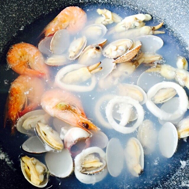 西班牙海鲜饭#有个故事#,把海鲜洗净倒入锅中、加适量清水和盐、少许白葡萄酒煮开