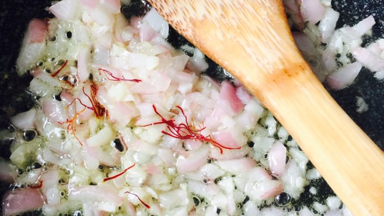 西班牙海鲜饭#有个故事#,锅里倒入适量橄榄油、加入切好的洋葱碎和蒜末爆香、把藏红花也放进去