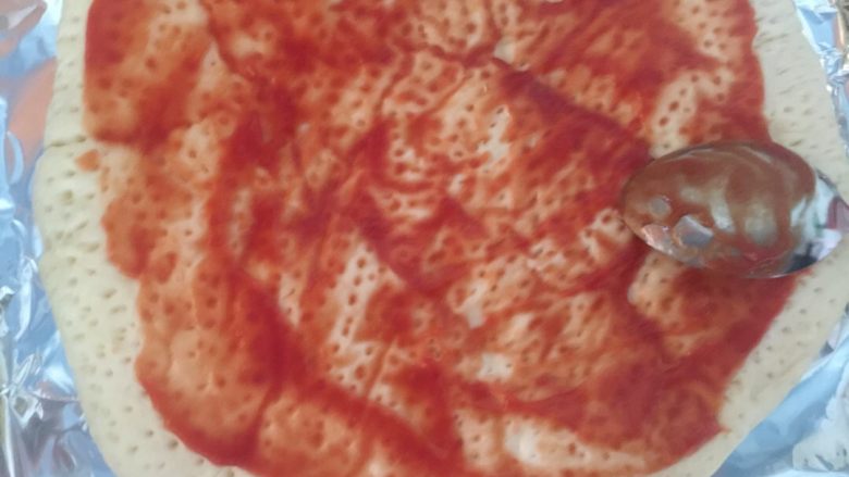 火腿虾仁蘑菇披萨,从冰箱拿出之前制作好的饼皮不用解冻，涂一层番茄沙司