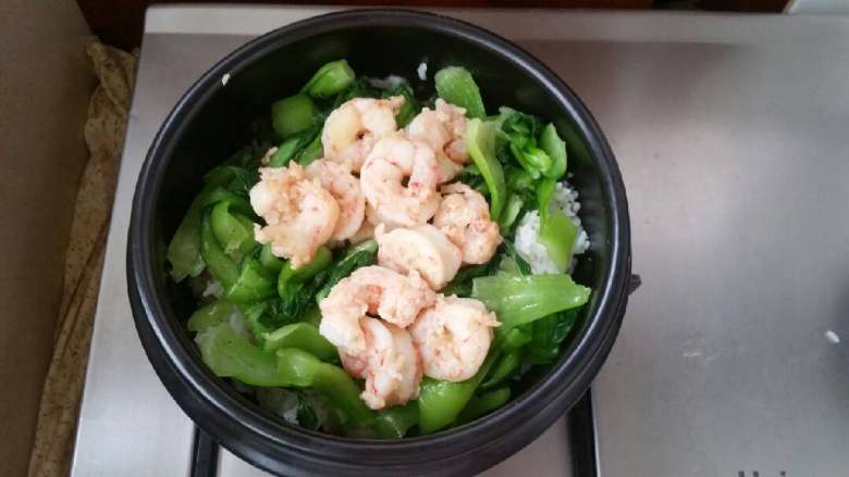 石锅芝士海鲜拌饭,米饭上铺匀小油菜，放入炒好的虾仁。