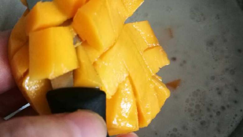 芒果西米捞,把果皮外翻后，用小刀取下芒果丁放入冷却后的西米露里。