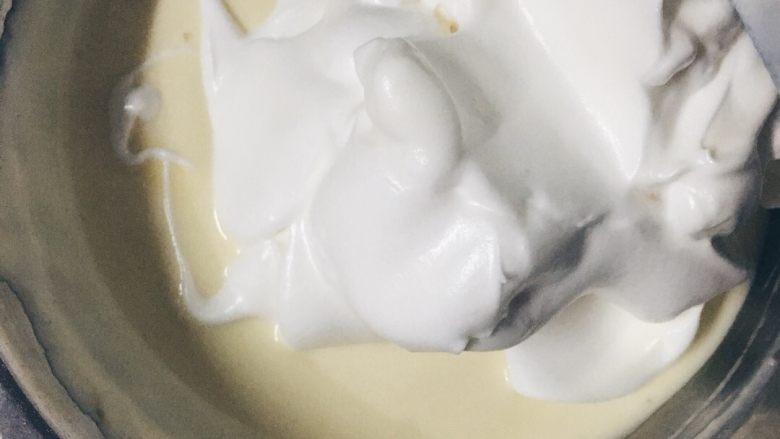酸奶戚风蛋糕,再将剩下的蛋白霜倒入，搅拌成细致均匀的戚风面糊。倒入6寸蛋糕模具八分满，入模具后震两下。（震出多余的气泡）