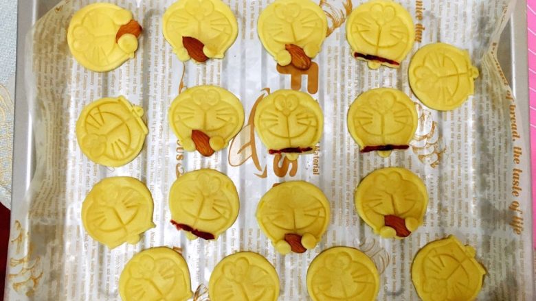 柠檬饼干（哆啦A梦）,把印好的饼干放在烤盘上。（最后剩余了一个面团，把它揪成一个个小小的圆球拿出杏仁按在了饼干上)