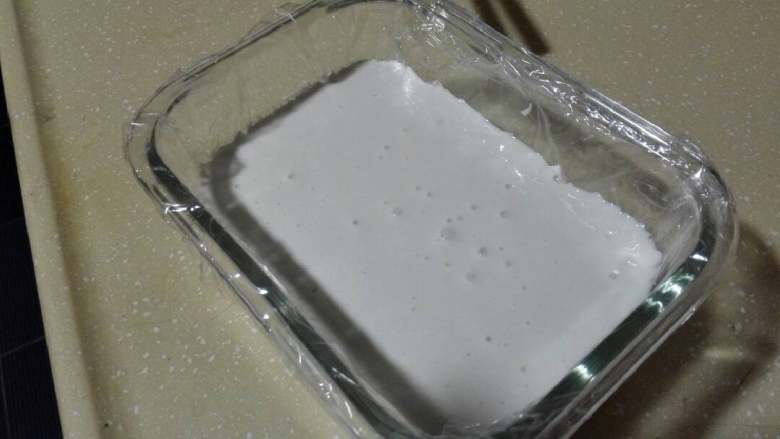 粘米粉牛奶发糕,拌均成粉浆，倒入垫上保鲜膜的饭盒中，盖好盖子，发酵至2倍大。