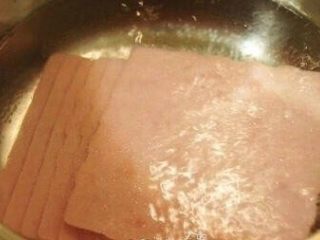 鸡蛋吐司 小热狗,将火腿切片放入锅中油煎一下！煎成外焦里嫩即可。如果不想太油，可以将火腿切片放入开水锅中过下水！