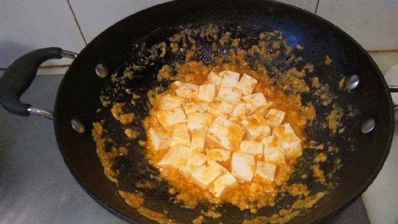 咸蛋黄豆腐,两手抓着锅子，来回摇晃，使咸蛋黄裹满豆腐。