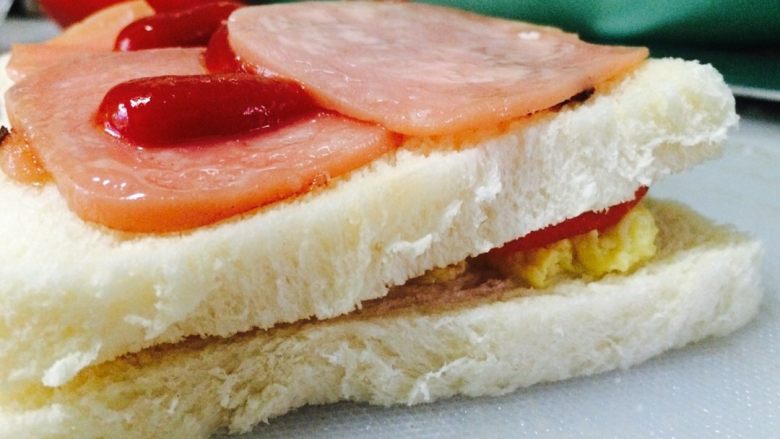 简易三明治,第二层放在火腿片和生菜，可以适量的挤上番茄酱或者沙拉酱。