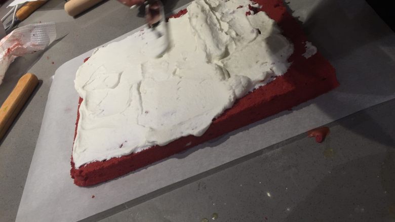 红丝绒蛋糕卷,蛋糕卷稍晾凉后用抹刀把打发好的奶油铺在蛋糕卷上，四边薄中间厚