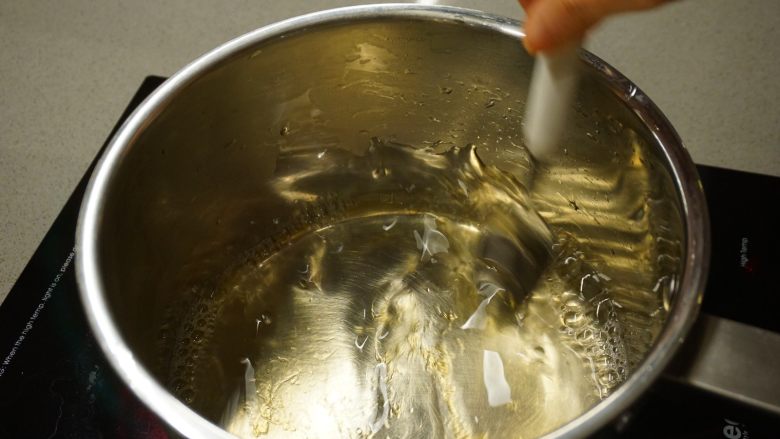 千层椰汁桂花糕,把浸软的鱼胶片放入热水中，轻轻搅拌使其彻底融化