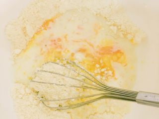 超快手的黑芝麻麻薯和蔓越梅麻薯,加入全蛋液、冷藏过的冰牛奶慢慢搅拌1分钟，再快速搅拌使其成团。