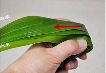 经典四角粽子包法详解，长寿米粽子 ,然后将漏斗后面的苇叶折过来盖上馅料，顺势用拇指食指卡捏着盖住两边。