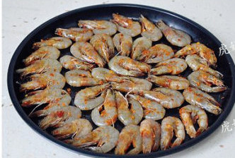 一烤即成的麻辣孜然脆皮虾,取出后将虾整齐的排入烤盘。